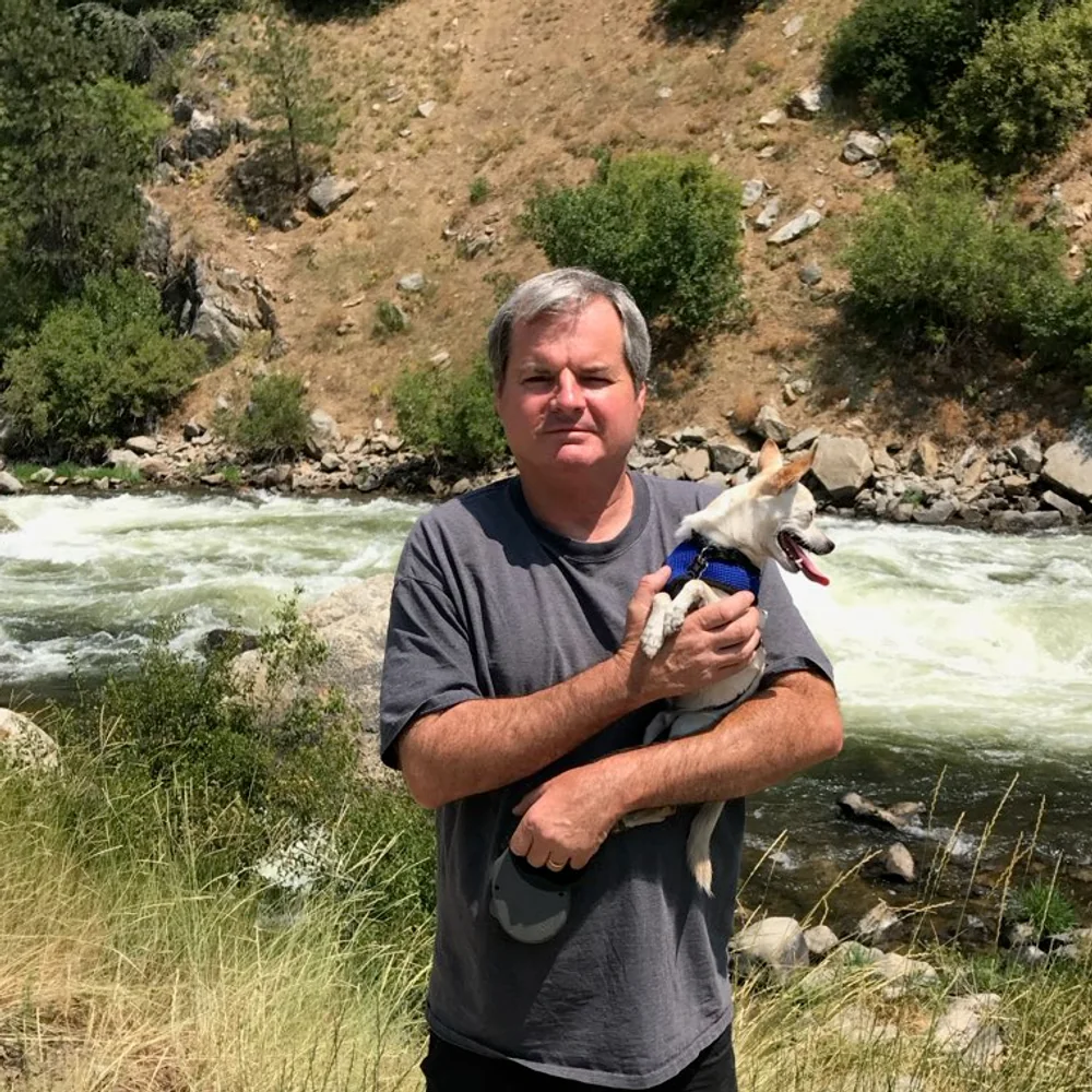 Ken Bushnell holding his dog beside a river